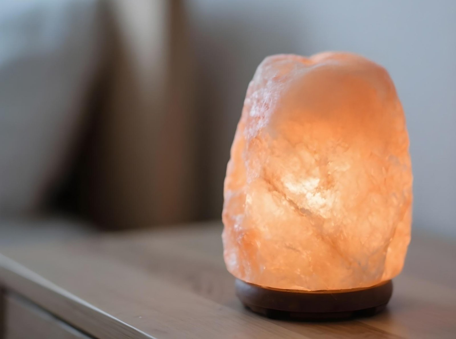 Himalayan salt lamp with natural wood base radiating gentle amber glow for peaceful home lighting.